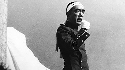 Wearing a military uniform, Mishima watches marchers.
